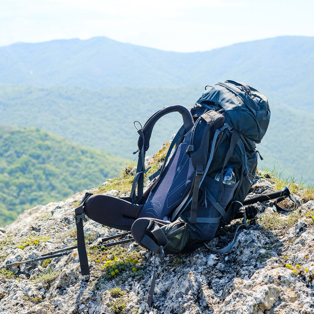 Dark blue backpack sitting on mountain rocks
