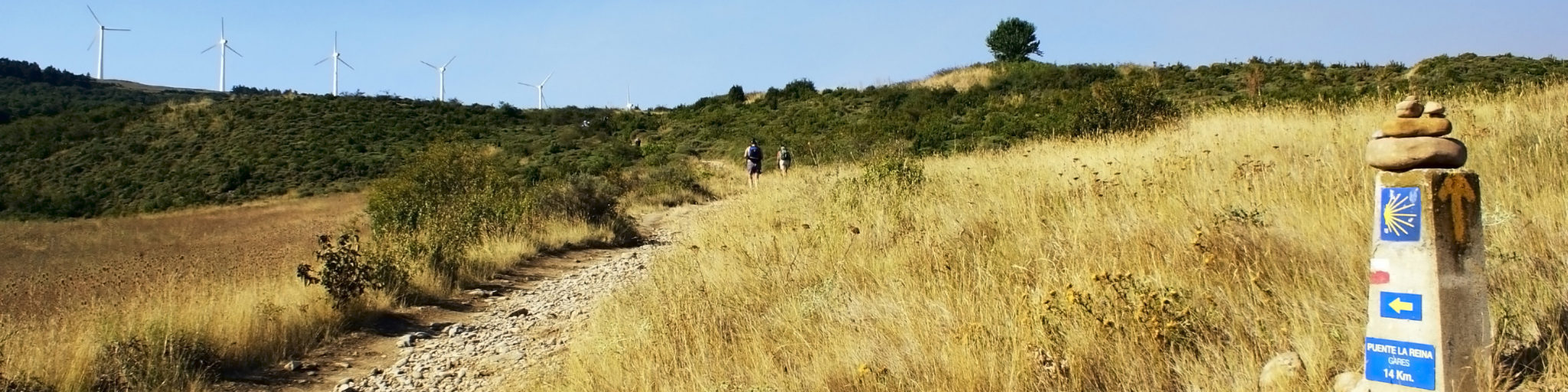 Hiking pilgrims pass by the signs of the Camino de Santiago.