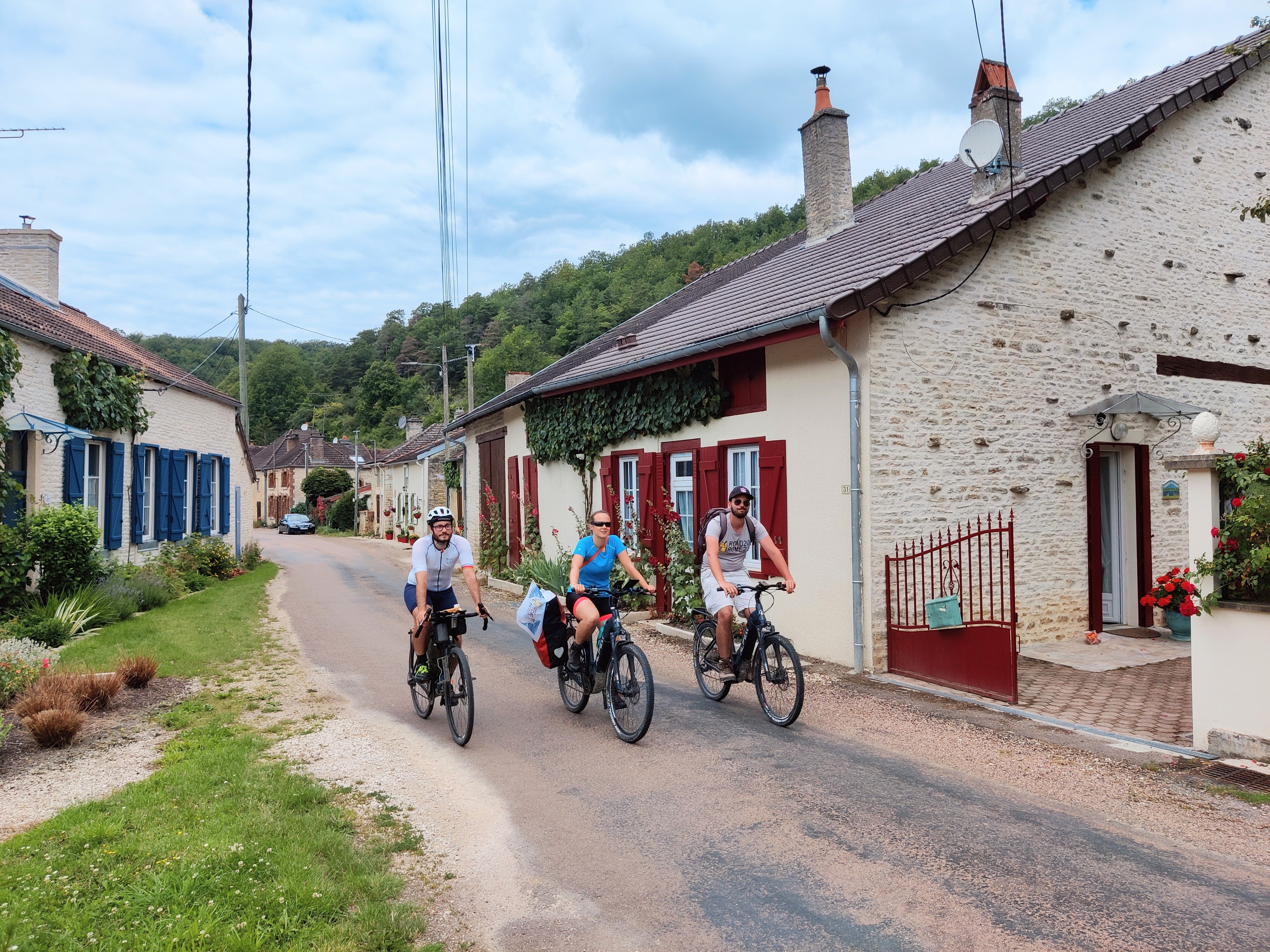 Three cyclists in a typical Alsace town along the Via Francigena pilgrimage route